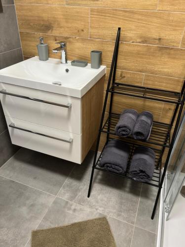 a bathroom with a sink and a shelf with towels at Hobití apartmán - Bilbo in Černá v Pošumaví