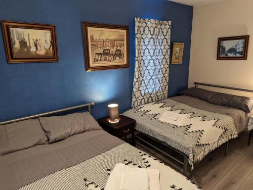 1 dormitorio con 2 camas y pared azul en Sherlock's house - 4 spacious bedroom 8 beds Private free parking & WIFI Accessibility Contractors Family with children & pets welcome en Burton upon Trent