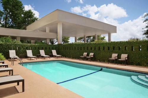 una piscina con sillas y una casa en Embassy Suites Brunswick, en Brunswick