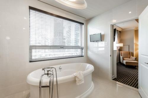 baño blanco con bañera y ventana en Le St-Martin Hotel Centre-ville – Hotel Particulier en Montreal