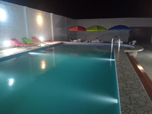 uma piscina com cadeiras e guarda-sóis num quarto em La casa de Maria- Playa Huanchaquito em Huanchaquito