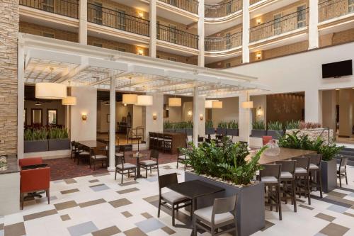 a lobby of a hotel with tables and chairs at Embassy Suites Baton Rouge in Baton Rouge
