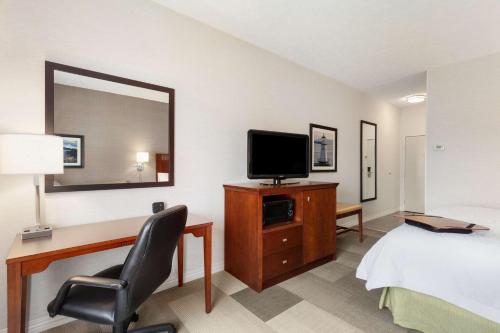 a hotel room with a bed and a desk with a television at Hampton Inn Burlington - Colchester in Burlington