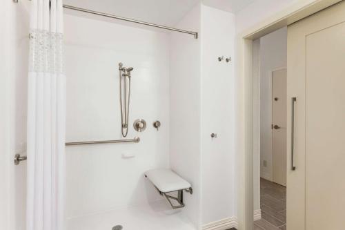 a white bathroom with a shower and a bench at Hampton Inn Burlington - Colchester in Burlington