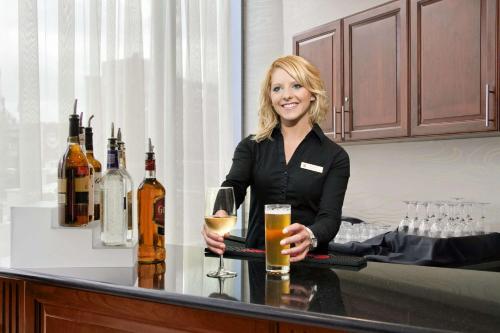 a woman standing at a bar with a glass of wine at Embassy Suites Buffalo in Buffalo