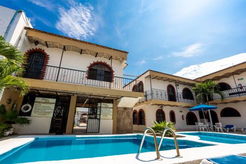 a villa with a swimming pool in front of a building at Bungalows Maria Teresa in Rincon de Guayabitos