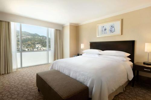 a hotel room with a large bed and a large window at Embassy Suites Los Angeles Glendale in Glendale