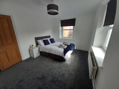a bedroom with a bed with blue pillows and a window at Ennerdale Edge - 4 Bed House in Cleator Moor
