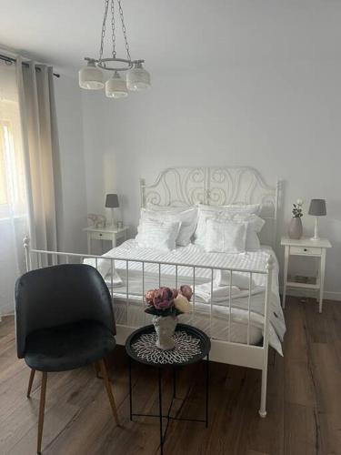 a bedroom with a white bed with a chair and a table at Apartament 3 camere in Baia Mare