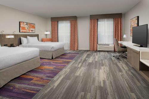 a hotel room with two beds and a flat screen tv at Hilton Garden Inn Columbia Airport, SC in Columbia