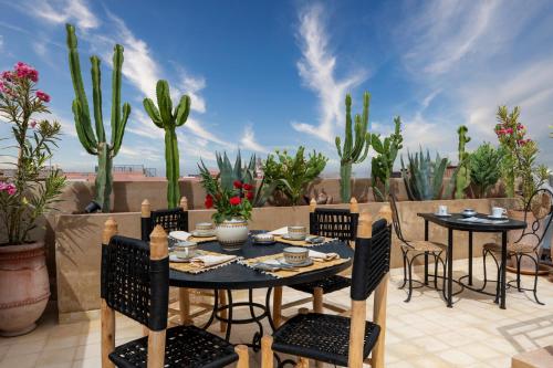 une terrasse avec une table, des chaises et un cactus dans l'établissement Riad Celema & Spa, à Marrakech