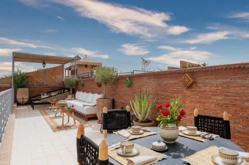 d'une terrasse avec une table, des chaises et un mur en briques. dans l'établissement Riad Celema & Spa, à Marrakech