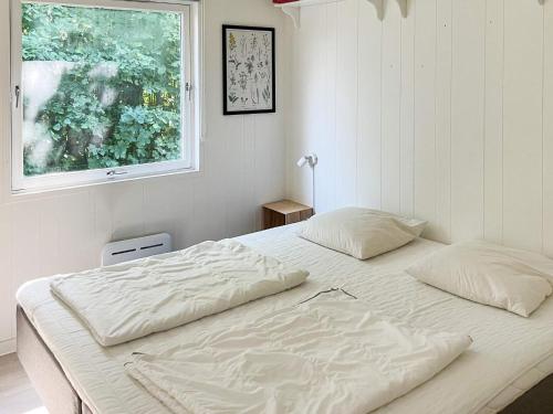 ein weißes Bett in einem Schlafzimmer mit einem Fenster in der Unterkunft Holiday home Højby III in Højby