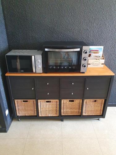 un four micro-ondes assis au-dessus d'une table avec des paniers dans l'établissement Les saisies-gîte les carolos, aux Saisies