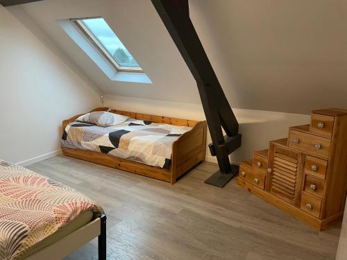 - une chambre mansardée avec un lit et une lucarne dans l'établissement Gite La Choupette, à Saint-Hilaire-du-Harcouët