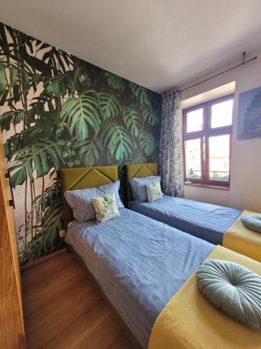 2 camas en un dormitorio con papel pintado tropical en APARTAMENTY TR 11 Apartament nr 1, en Olsztyn