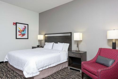 a hotel room with a bed and a red chair at Hampton Inn Akron-South in Akron