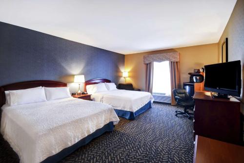 a hotel room with two beds and a flat screen tv at Hampton Inn Chicopee - Springfield in Chicopee