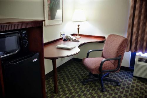 a hotel room with a desk and a chair and a television at Hampton Inn Carrollton in Carrollton