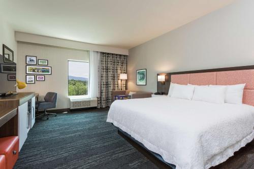 a hotel room with a large bed and a desk at Hampton Inn Cumberland in Cumberland