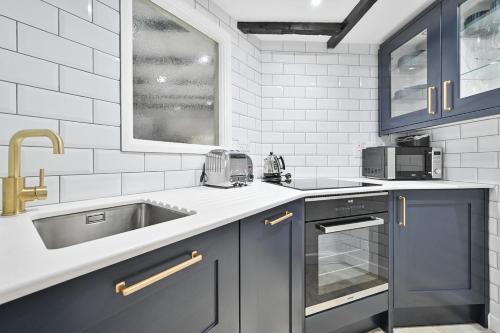 una cocina con armarios azules y fregadero en Luxury Couple's Getaway with River Views and Parking en Polperro