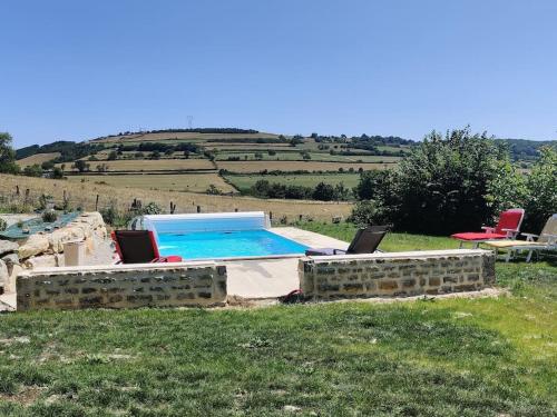 a swimming pool in a field with two chairs at gîte dans ancien moulin 