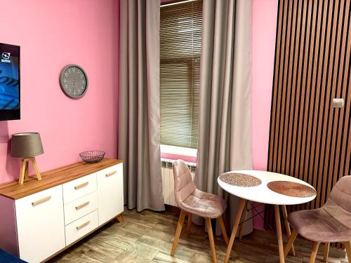 um quarto com paredes cor-de-rosa, uma mesa e cadeiras em Apartament Krasnostawski em Krasnystaw