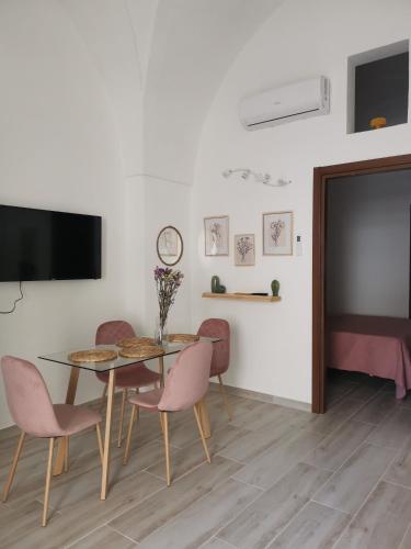 Un comedor con mesa y sillas y un televisor de pantalla plana. en LeVolte, en Brindisi