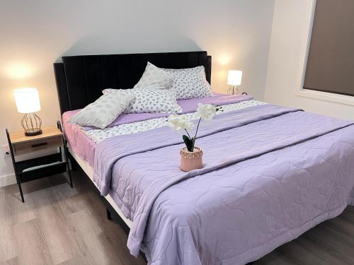 a bed with a purple comforter and a vase with flowers at Private Entire Townhouse Retreat Close to Lake in Calgary