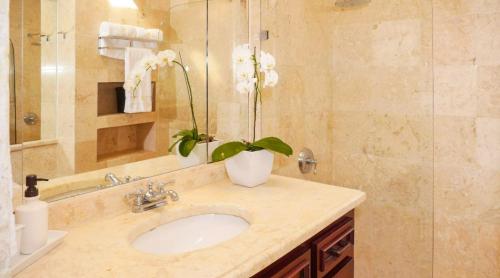 ein Badezimmer mit einem Waschbecken und einer Vase mit Blumen darauf in der Unterkunft Sunny Vacation Villa No 84 in San Rafael del Yuma