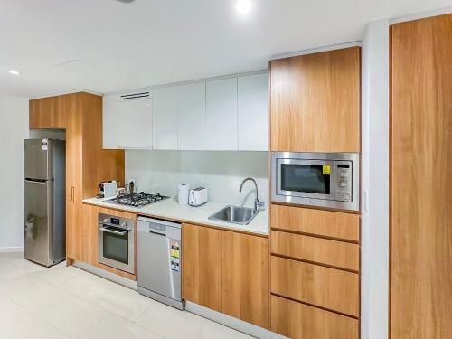 a kitchen with stainless steel appliances and wooden cabinets at Brisbane Skytower By Utopia in Brisbane