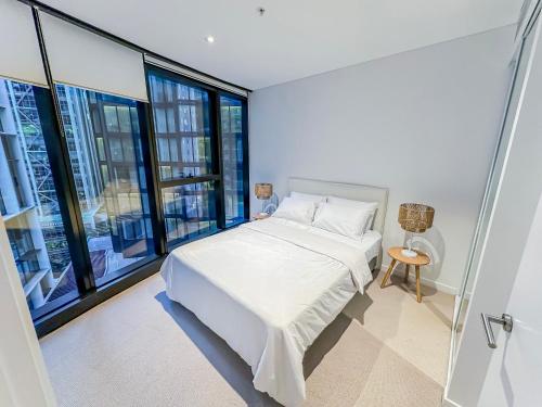 a bedroom with a white bed and large windows at Brisbane Skytower By Utopia in Brisbane