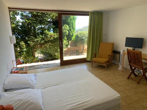 Schlafzimmer mit einem Bett, einem Schreibtisch und einem Fenster in der Unterkunft Maison Gaou Benat, magnifique vue mer in Bormes-les-Mimosas