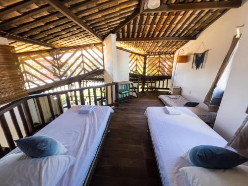 two beds in a room with wooden ceilings at Localização Incrível - Praia e Vila in Praia do Forte