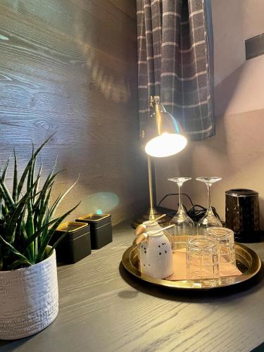a table with a lamp and a plate with glasses on it at La Rêverie de Thumel - Suite in Rhêmes-Notre-Dame