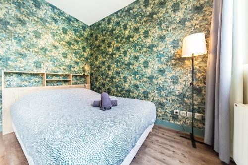 een slaapkamer met een bed in een kamer met bloemenbehang bij Le Guérin cosy studio 2 pers Tête d'Or in Villeurbanne
