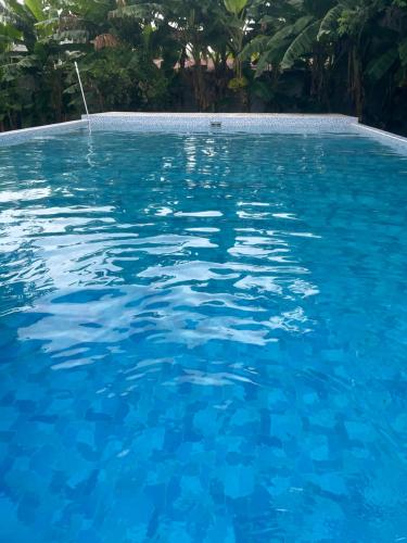 ein Pool mit blauem Wasser und Bäumen im Hintergrund in der Unterkunft Hotel Chulamar, Piscina y Restaurante in Escuintla