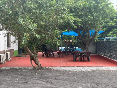 Hotel Chulamar, Piscina y Restaurante في Escuintla: مجموعة طاولات وكراسي تحت شجرة