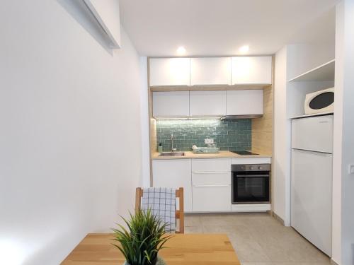 a small kitchen with white cabinets and a wooden table at Antic Manresa 2 in Manresa