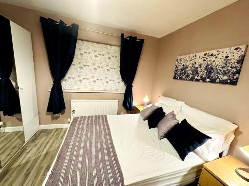 een slaapkamer met een bed met zwarte gordijnen en een raam bij NKN cosy maisonette close to train station, food, shopping in Kent