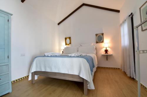 a white bedroom with a bed with white sheets and pillows at La Casa de Reyes in Peñaflor