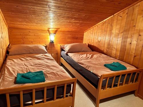 two beds in a wooden cabin with a light on at Chalet Hildegard in Plaffeien
