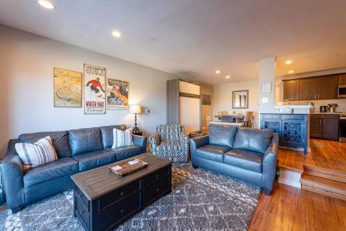 a living room with blue couches and a kitchen at Great Location! Downtown WP with Hot Tub! Sleeps 6! in Winter Park