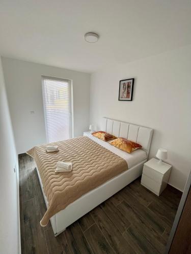 a white bedroom with a large bed and a window at Azzurro Apartman Srebrno Jezero in Veliko Gradište
