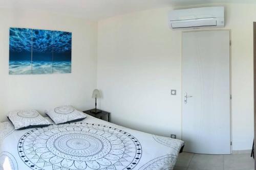 une chambre blanche avec un lit et un tableau sur le mur dans l'établissement Haut de villa 2P, jardin, clim, prise VL Electrique, à Saint-Paul-de-Vence