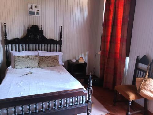 um quarto com uma cama com uma cabeceira de madeira e uma cadeira em CASA DA VOVÓ CÉU - Casa de Campo Gandaresa - Country House, entre COIMBRA e AVEIRO, a 15 minutos carro Praia Mira - Quintal com piscina desmontável em Castanhede