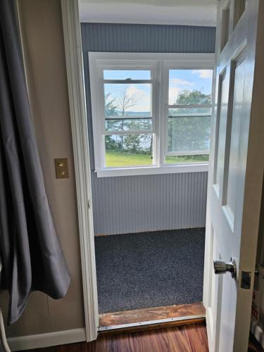 a room with two windows and a hallway with a door at Lake Shore Farm Inn in Northwood
