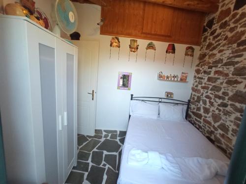 - une chambre avec un lit dans une pièce dotée d'un mur en pierre dans l'établissement Stone house Anatoli, à Mesokhória