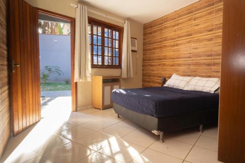 a bedroom with a bed and a wooden wall at Casa Jaguar suites 150 mt da praia geriba in Búzios