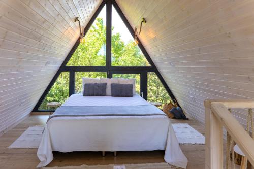 Bett in einem Zimmer mit einem großen Fenster in der Unterkunft Grafit Kabin in Nagykanizsa